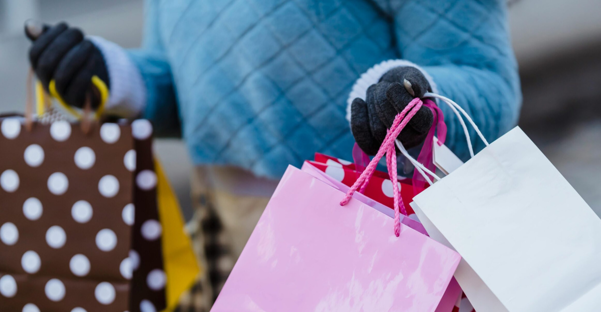 Crop anonymous female in blue soft sweater with many different colorful gift bags on blurred background
