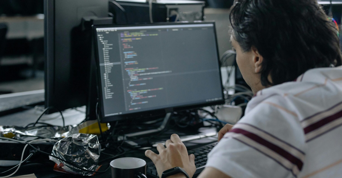 Man focused on coding at his workstation in a modern office.