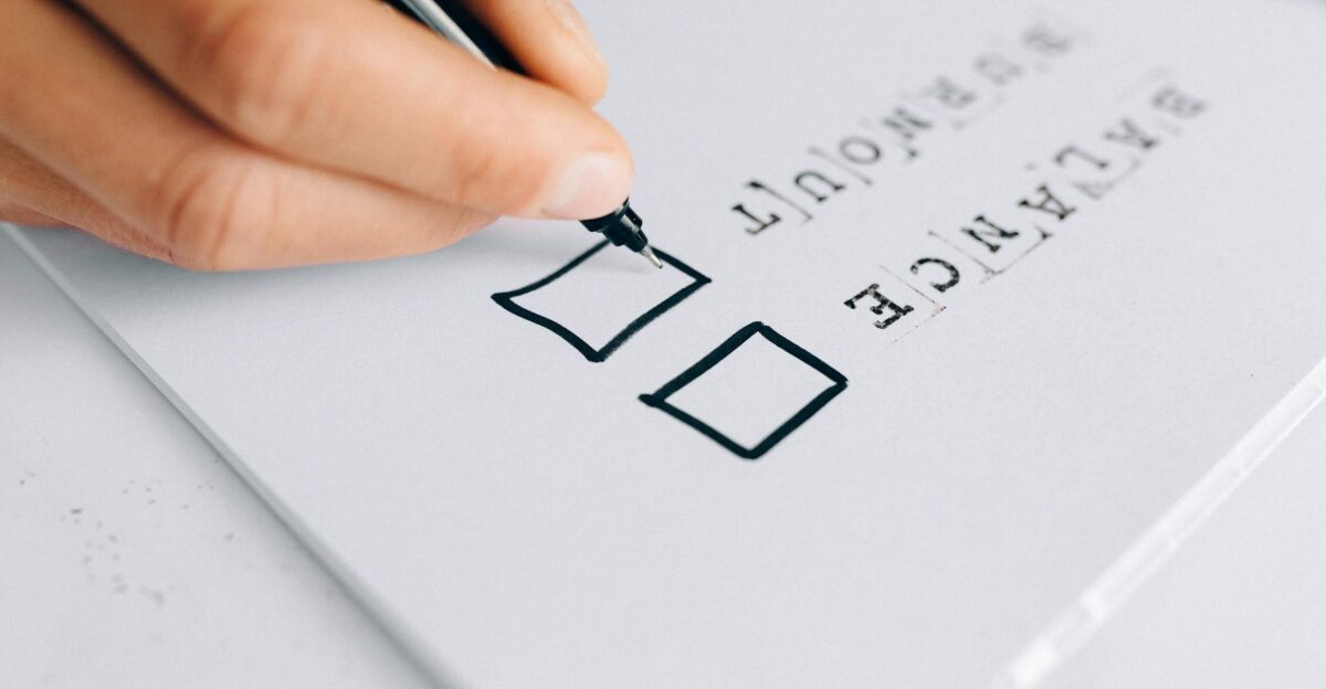 A hand drawing checkboxes on a checklist themed around balance and burnout