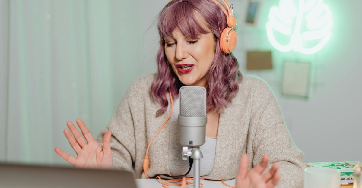 Woman podcasting indoors with headphones and microphone engaging in recording or live stream