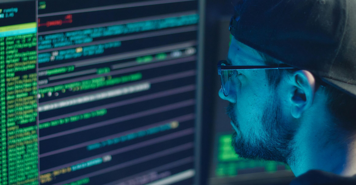 A cybersecurity expert inspecting lines of code on multiple monitors in a dimly lit office.