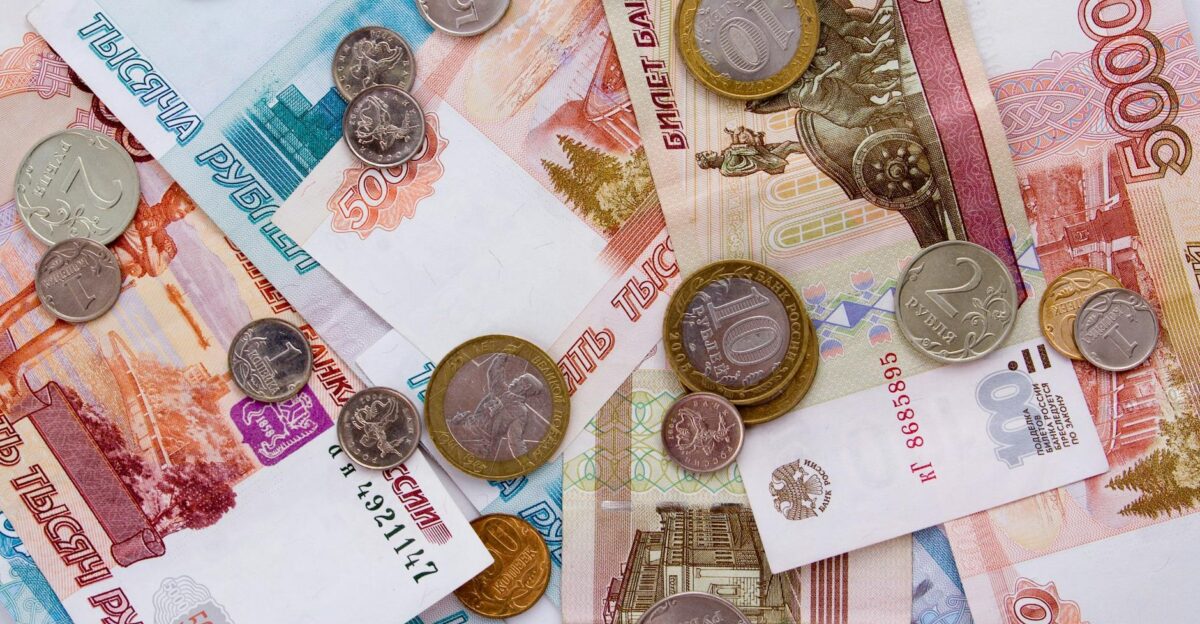 A detailed image of Russian ruble banknotes with various coins scattered on top showcasing currency details