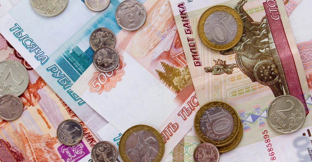 A detailed image of Russian ruble banknotes with various coins scattered on top, showcasing currency details.