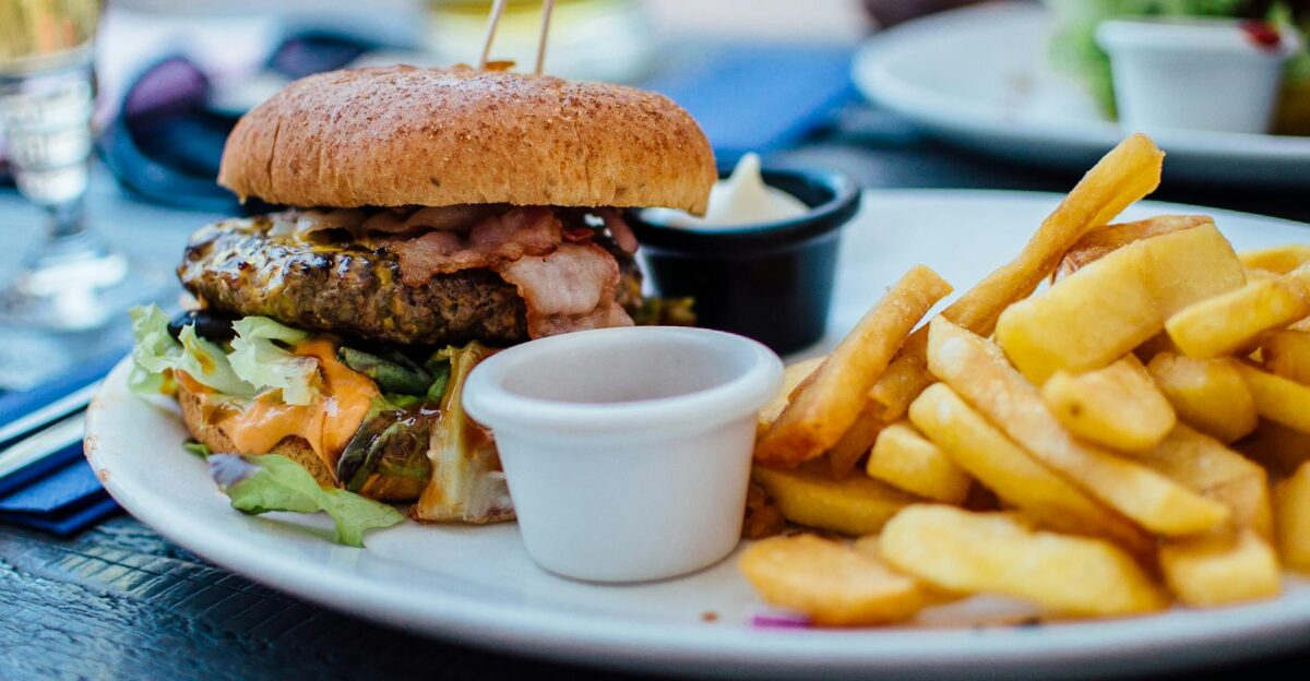 Close-up of a juicy burger and crispy fries served with sauces perfect for a hearty meal