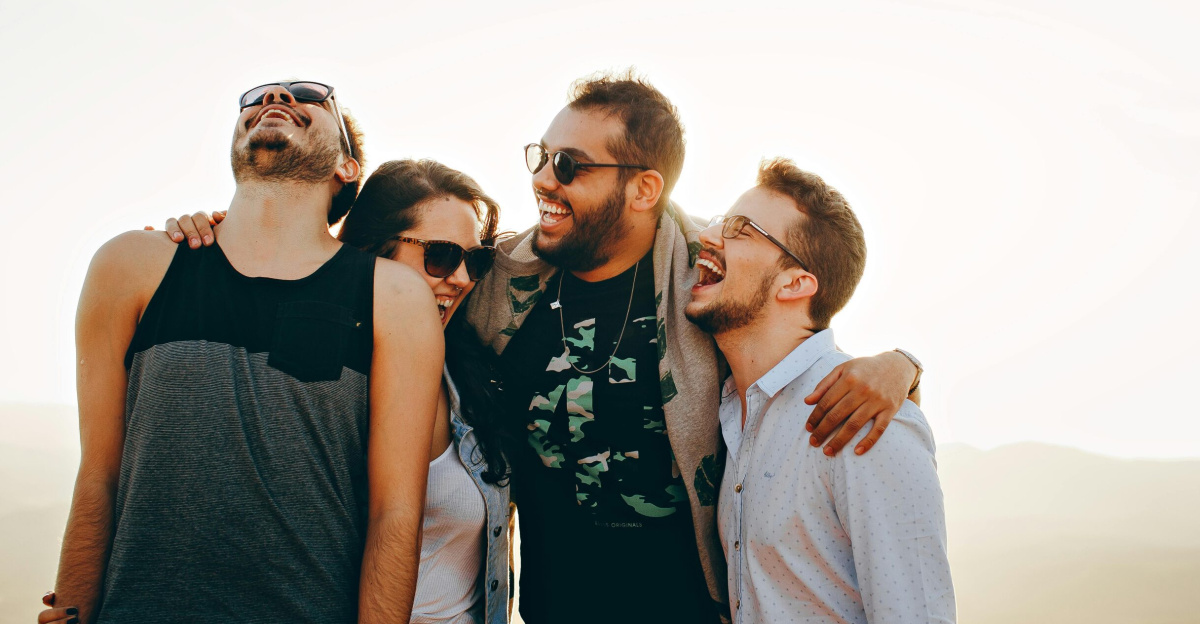 A group of young adults laughing and enjoying time together outdoors under the sun.