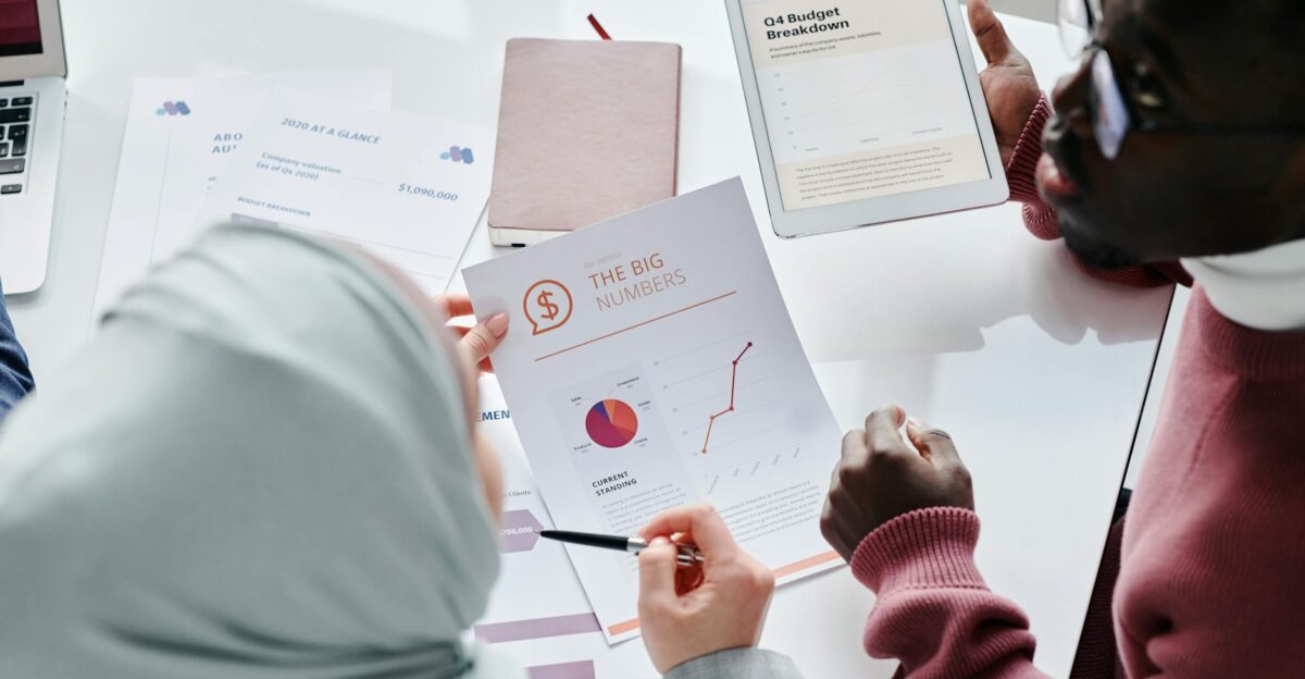 Two colleagues reviewing financial documents and graphs during an office meeting
