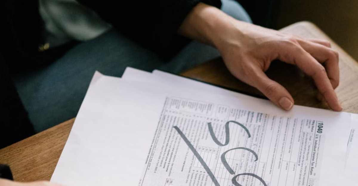 Close-up of hands examining documents marked scam with a calculator nearby