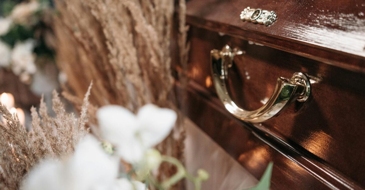 Close-up of a polished wooden casket adorned with floral arrangements symbolizing loss and remembrance