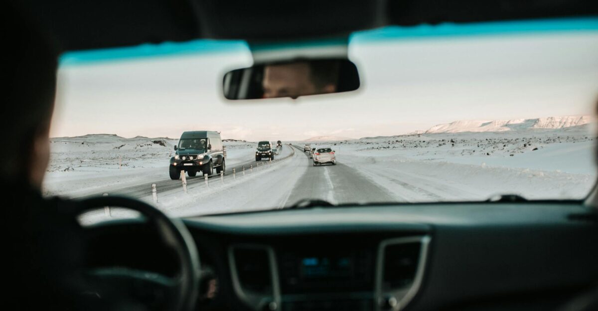 View from inside a car driving on a snowy road through a picturesque winter landscape