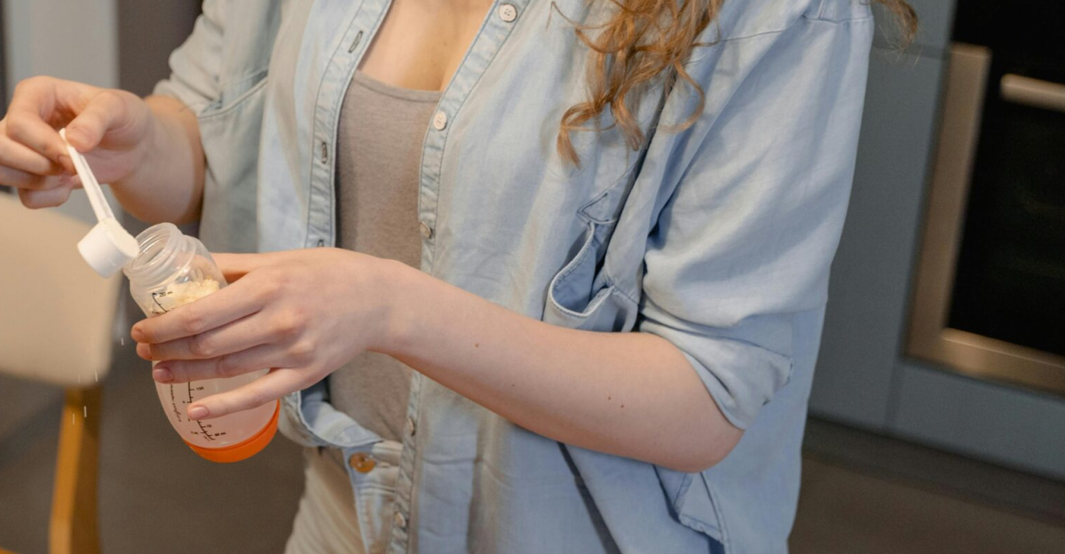 A woman prepares baby formula in a modern kitchen, captured during a daytime routine.
