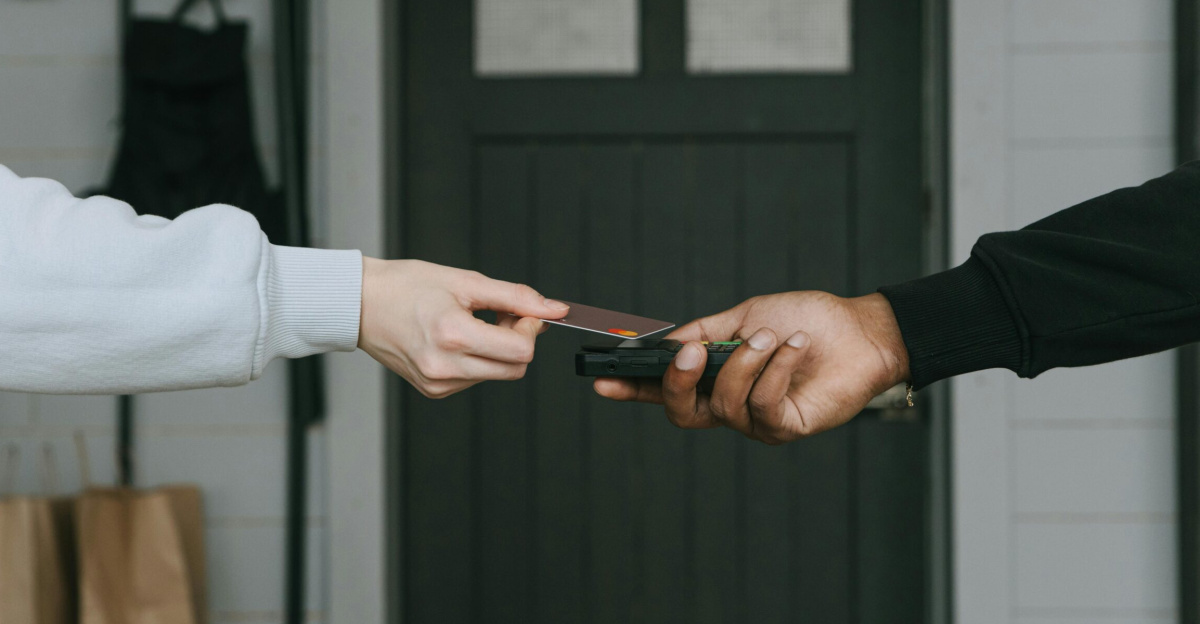 Close-up of hands making a contactless card payment indoors, highlighting cashless transaction technology.