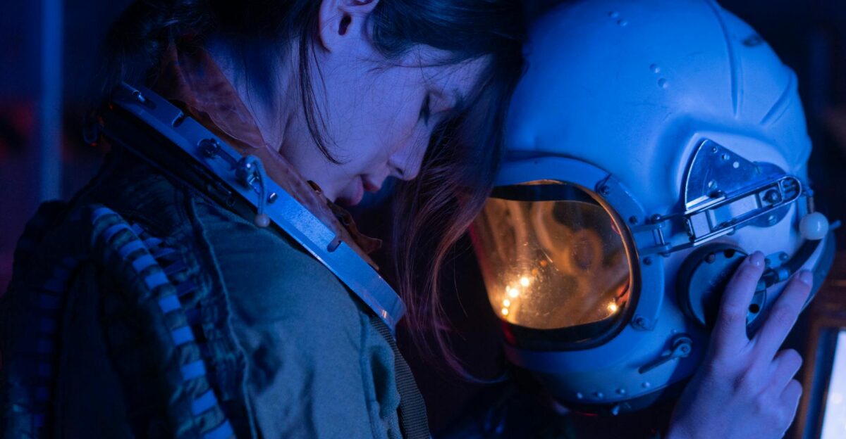 Dramatic blue-toned portrait of a woman cosmonaut holding her helmet with moody lighting