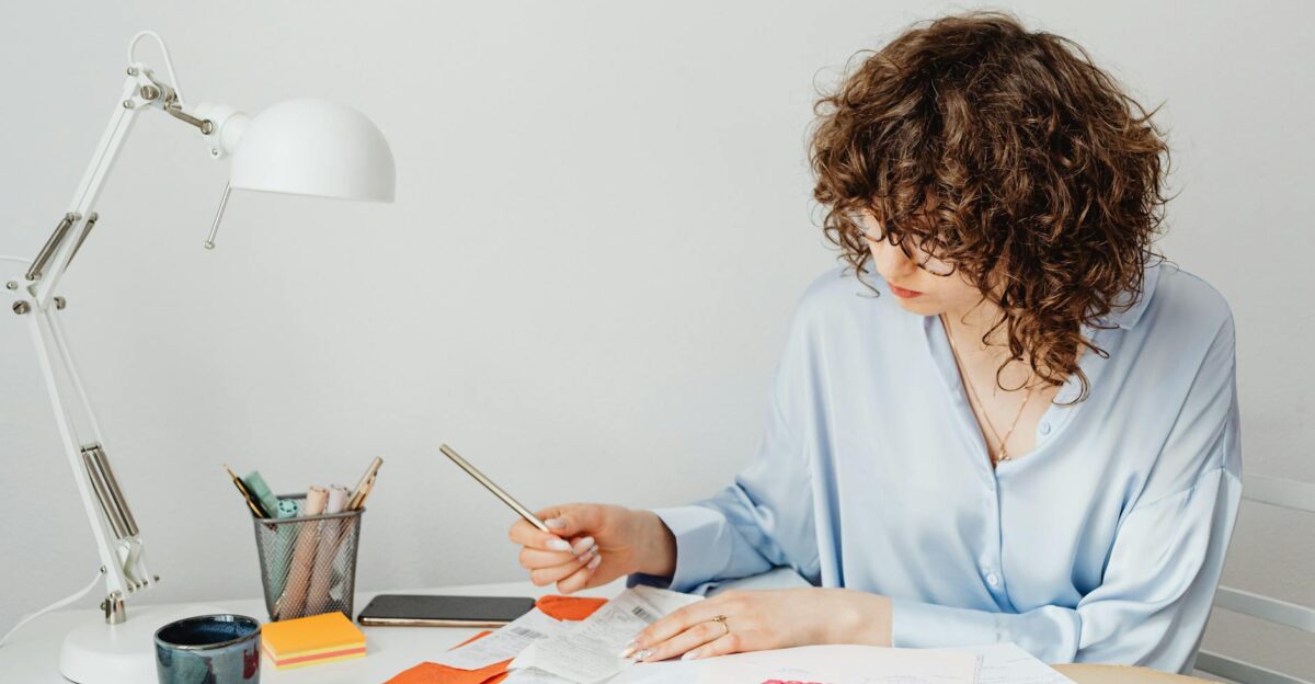 Woman in office calculating expenses with documents calculator and coffee