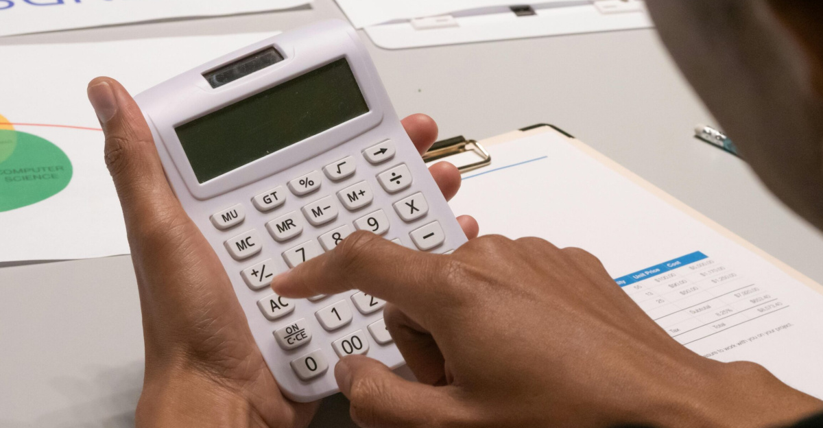 Focused image of a person using a calculator amidst financial documents and charts.