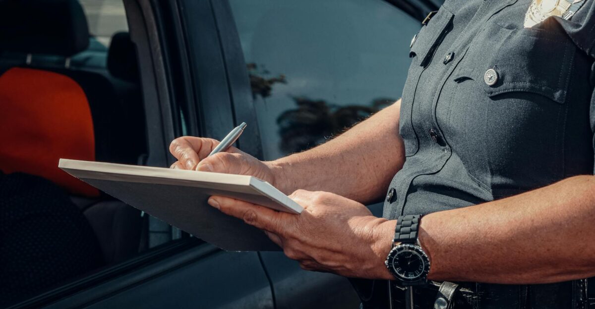 Close-up of a police officer writing a ticket by a car window Law enforcement scene