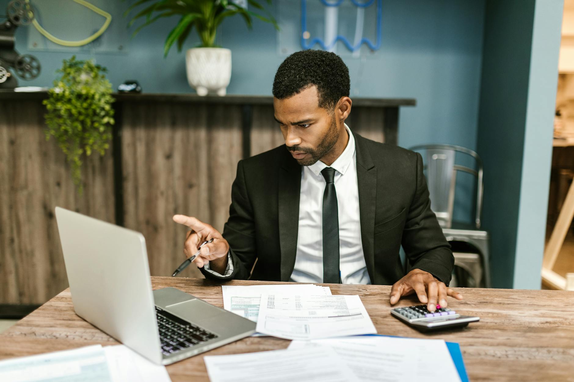 Professional man in a suit using a laptop and calculator in an office setting