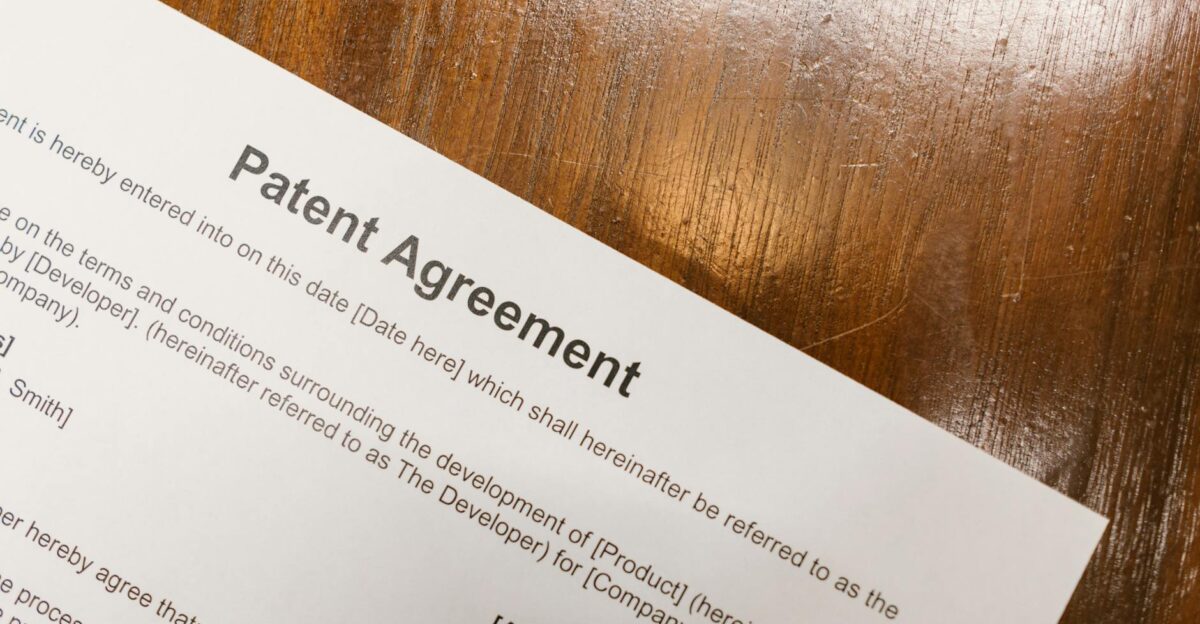 Detailed close-up of a patent agreement document on a polished wooden table