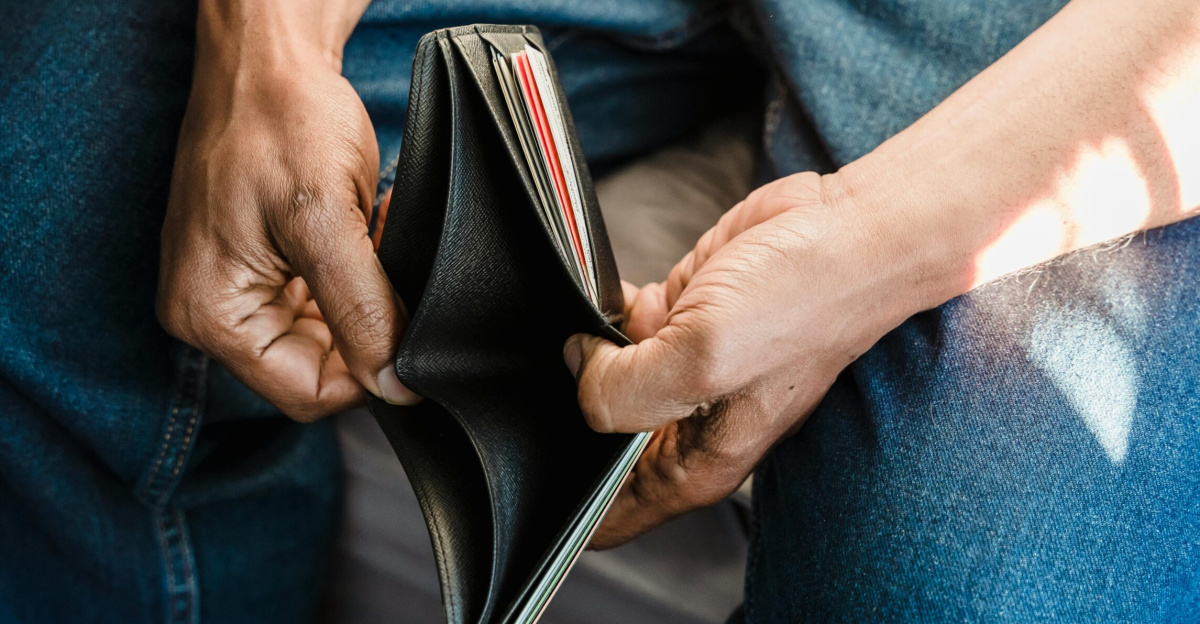 Close-up of a man holding an empty wallet, symbolizing financial crisis and hardship.