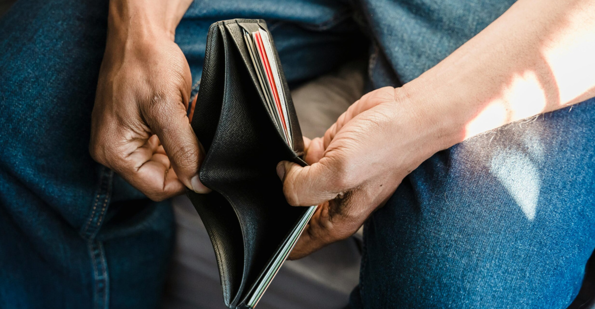 Close-up of a man holding an empty wallet, symbolizing financial crisis and hardship.
