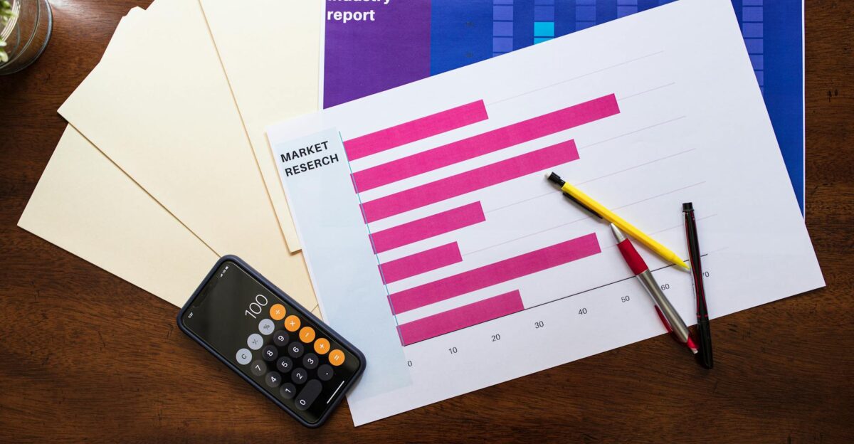 Top view of market research reports and calculator on a wooden desk illustrating business analysis
