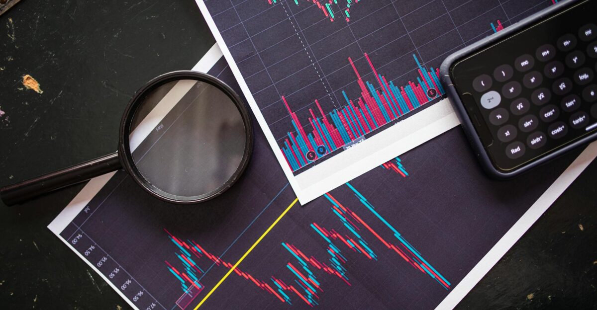 Stock market charts analyzed with a magnifying glass and calculator for financial research