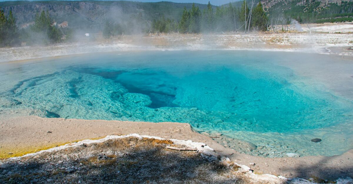 Stunning view of a vibrant turquoise hot spring with steam rising in Yellowstone National Park