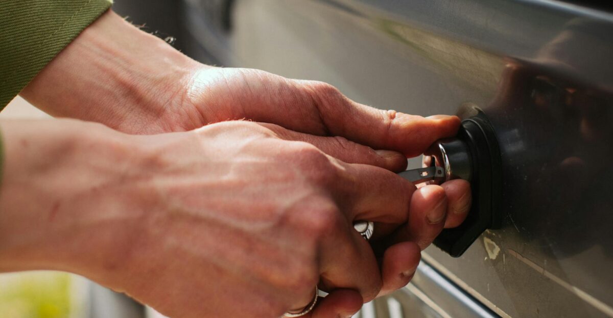 Close-up of hands unlocking a vehicle trunk with a key showing detail and reflection