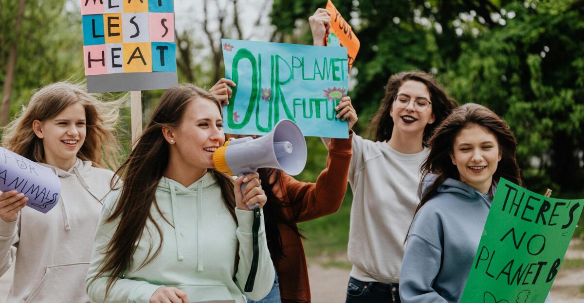 Group of young women at a climate protest holding signs with environmental messages outdoors