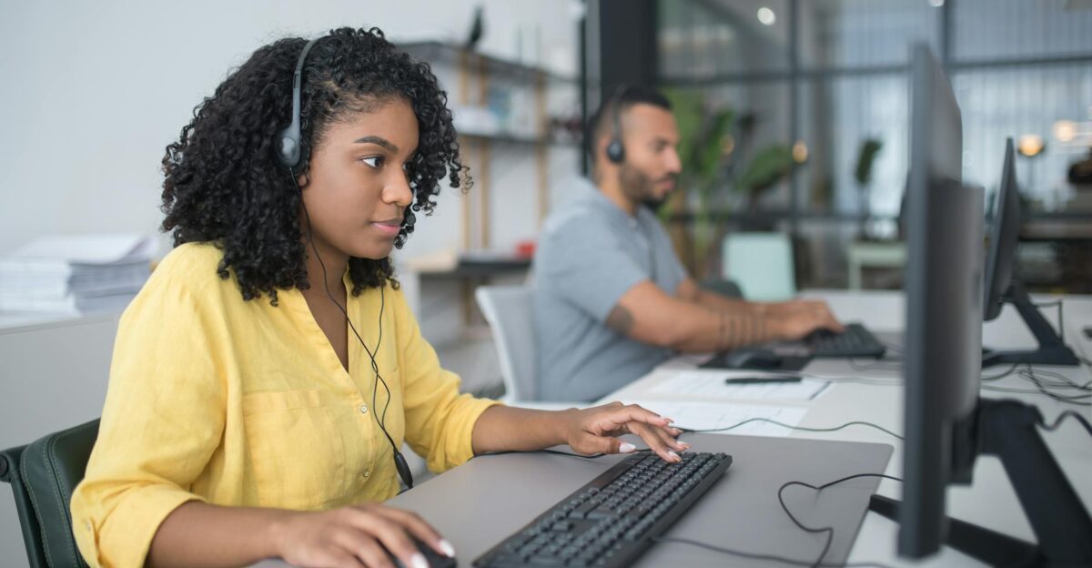 Two customer service agents working with headsets in a modern office setting