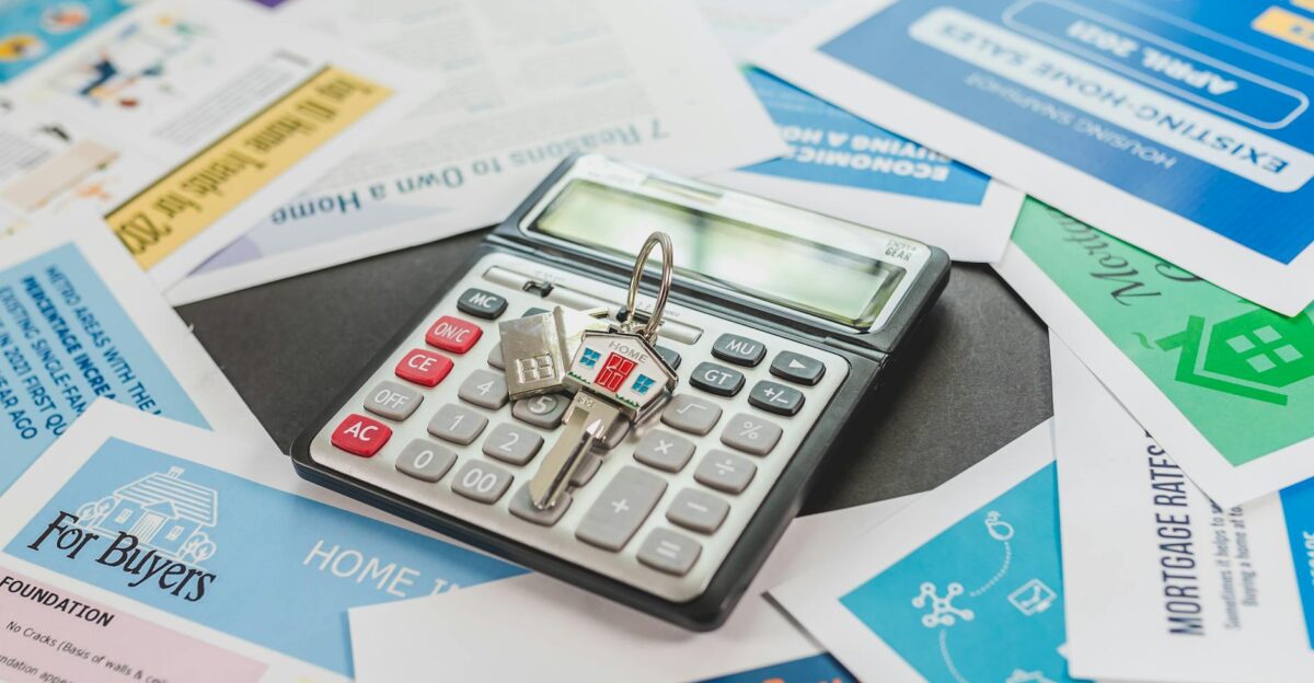 A calculator and real estate flyers depicting financial planning for home buyers