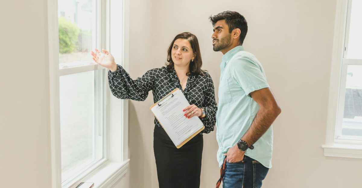 A real estate agent discusses property details with a client indoors highlighting the view through large windows