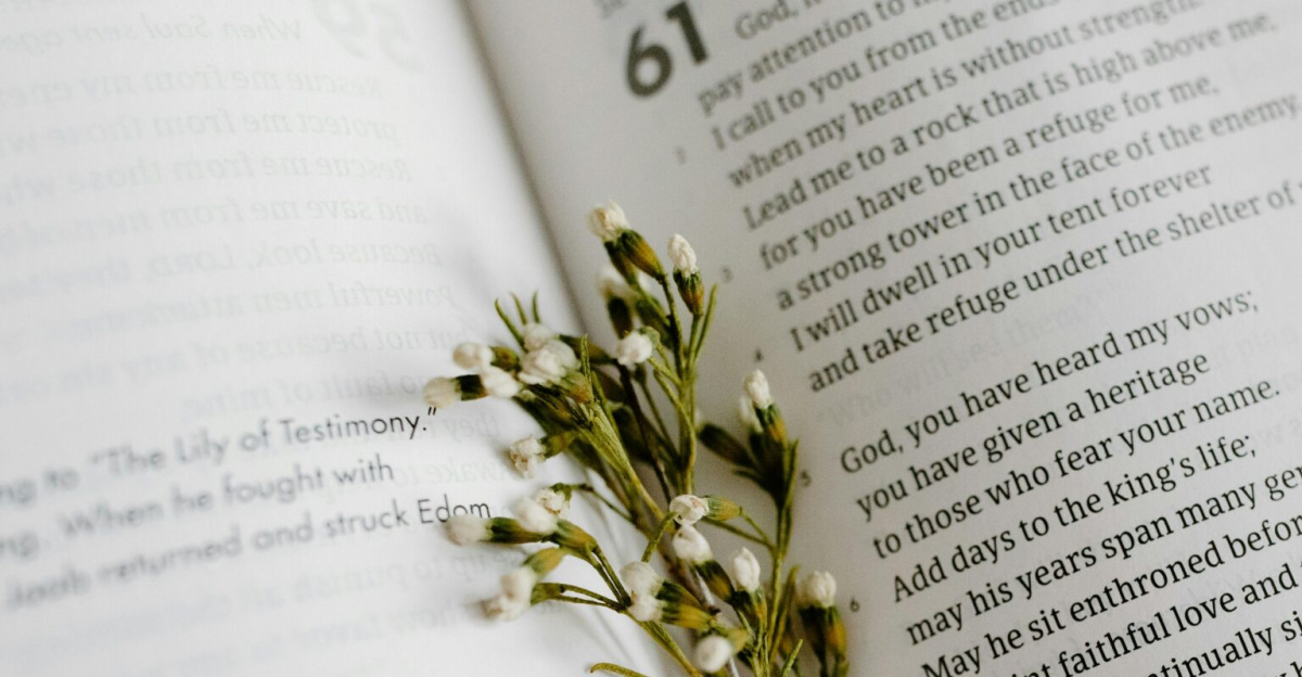 A close-up of an open Bible page with scripture and delicate white flowers.