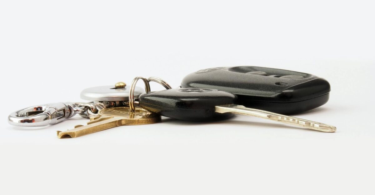 Detailed image of car keys on a white surface including a key fob and keychain