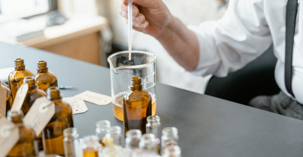 A person blends essential oils in glass bottles for aromatherapy indoors