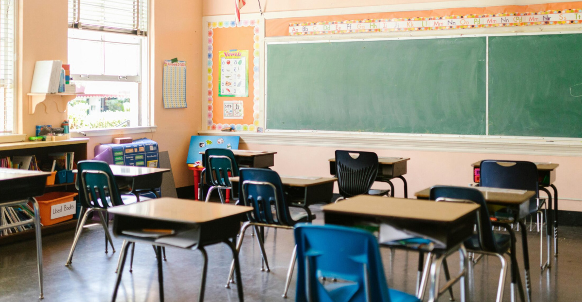 An inviting, sunlit classroom with empty desks and an American flag, ready for students.