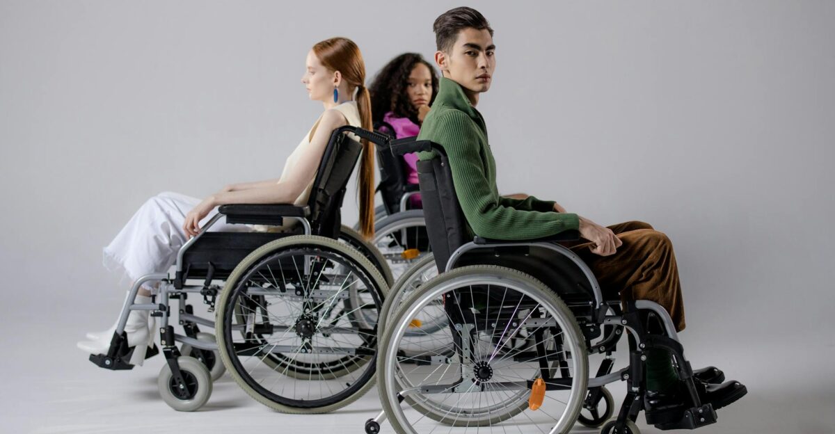 Three diverse individuals in wheelchairs posing indoors symbolizing inclusivity