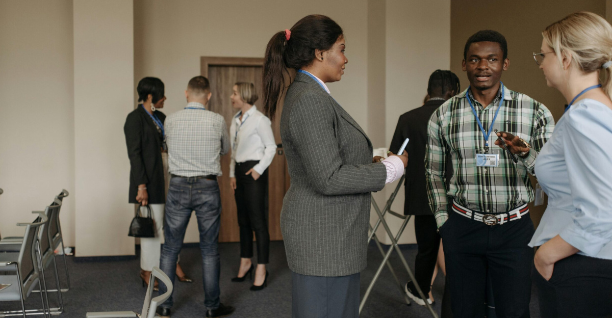 Professionals engaging in conversation at a diverse business conference with corporate attire indoors.