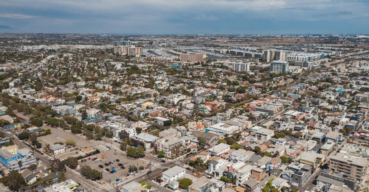 Aerial drone view of expansive urban cityscape with residential and commercial buildings under a blue sky