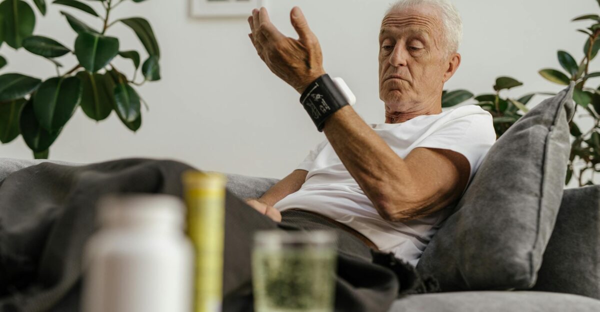 Elderly man checks his blood pressure using a wrist monitor in a comfortable living room setting