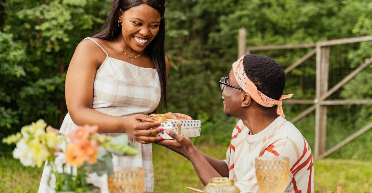 A joyful moment of gift exchange between friends at an outdoor summer gathering