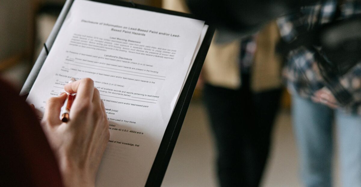 A couple examines real estate documents indoors with focus on writing and discussion