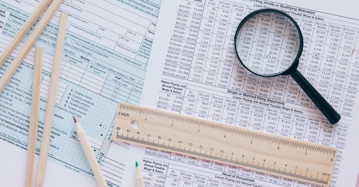 A high angle view showing IRS tax forms with pencils ruler and magnifying glass for financial planning