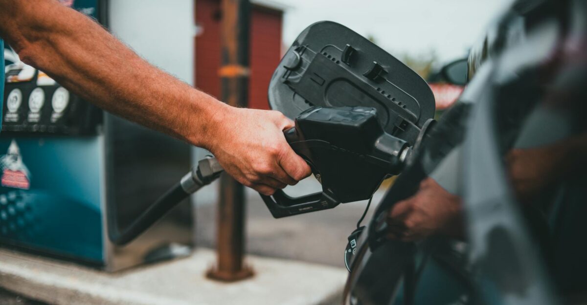 Close-up of a hand holding a nozzle while refueling a car at a gas station