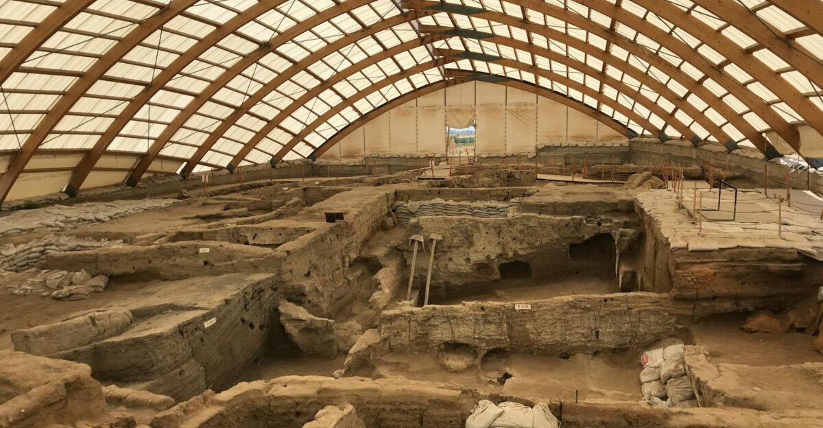 A large indoor archaeological dig showcasing ancient ruins under a protective dome structure