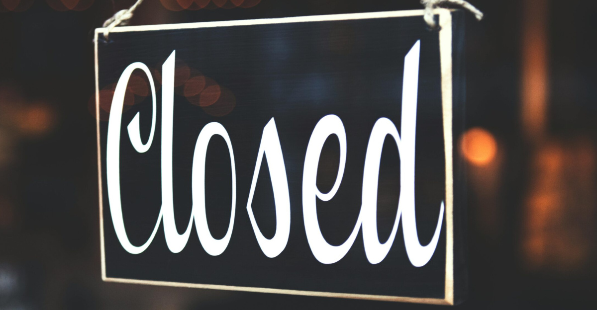 A close-up of a 'Closed' sign hanging against a blurred, bokeh background, creating a warm, inviting atmosphere.