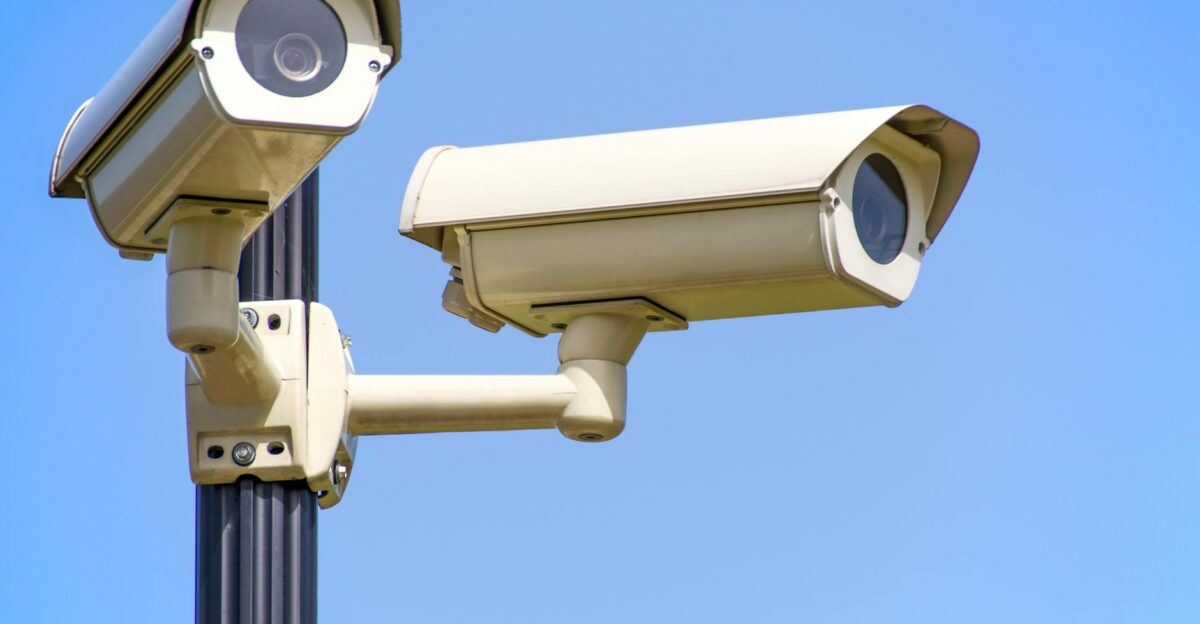 Outdoor security cameras mounted on a pole against a clear blue sky ensuring vigilant surveillance