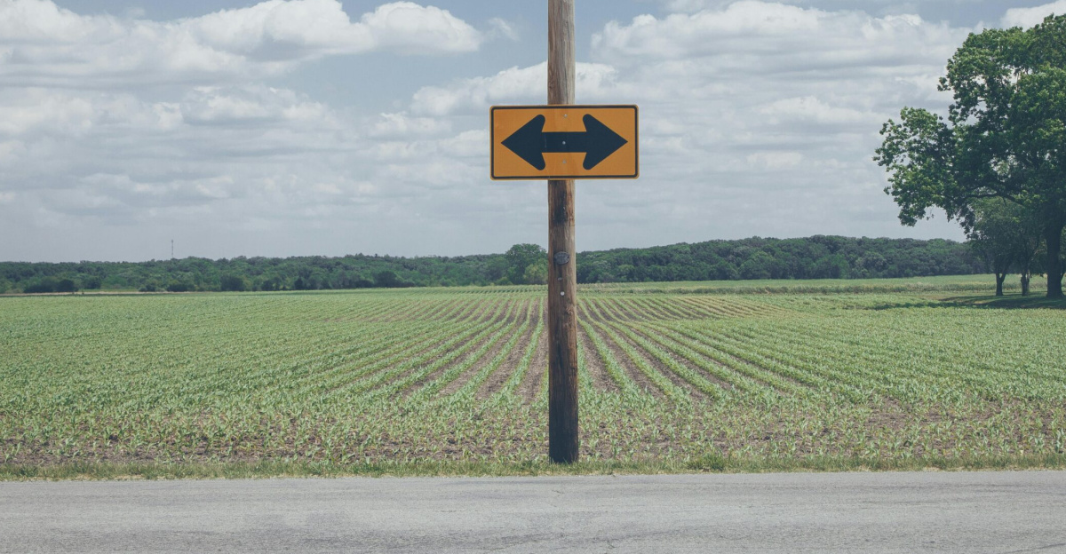 Scenic rural road sign on farmland with clear blue sky and clouds.