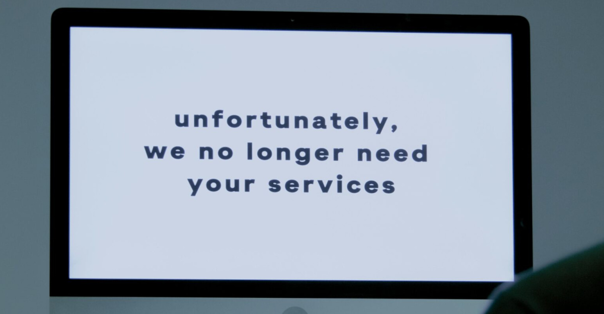 A computer screen displays a termination message, indicating job loss or unemployment.