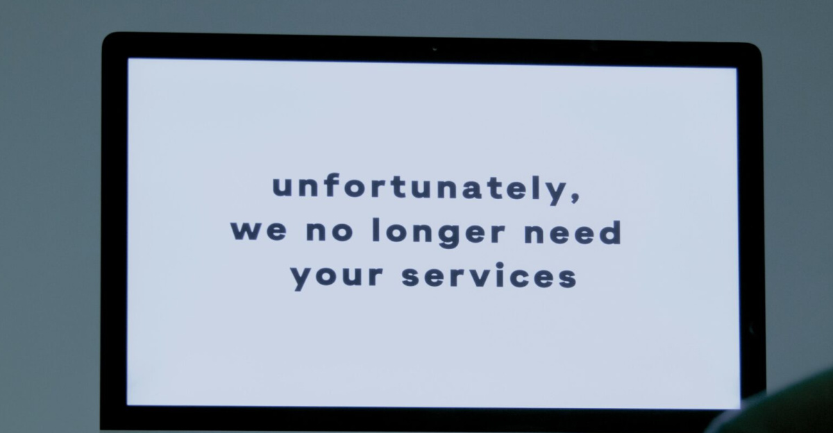 A computer screen displays a termination message, indicating job loss or unemployment.