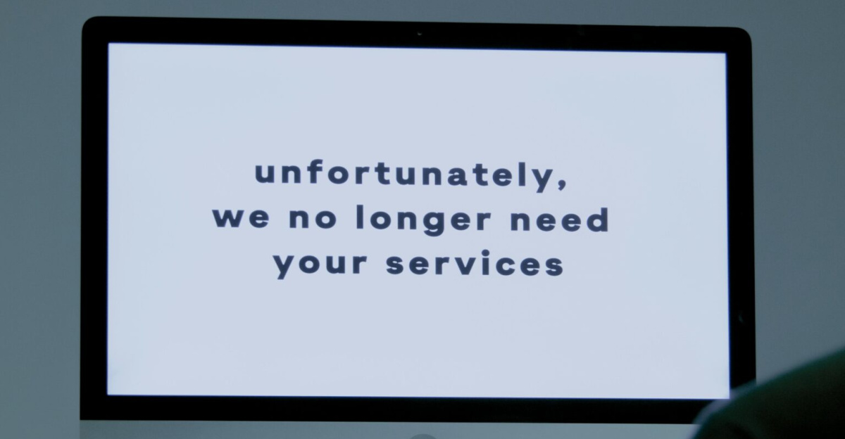 A computer screen displays a termination message, indicating job loss or unemployment.